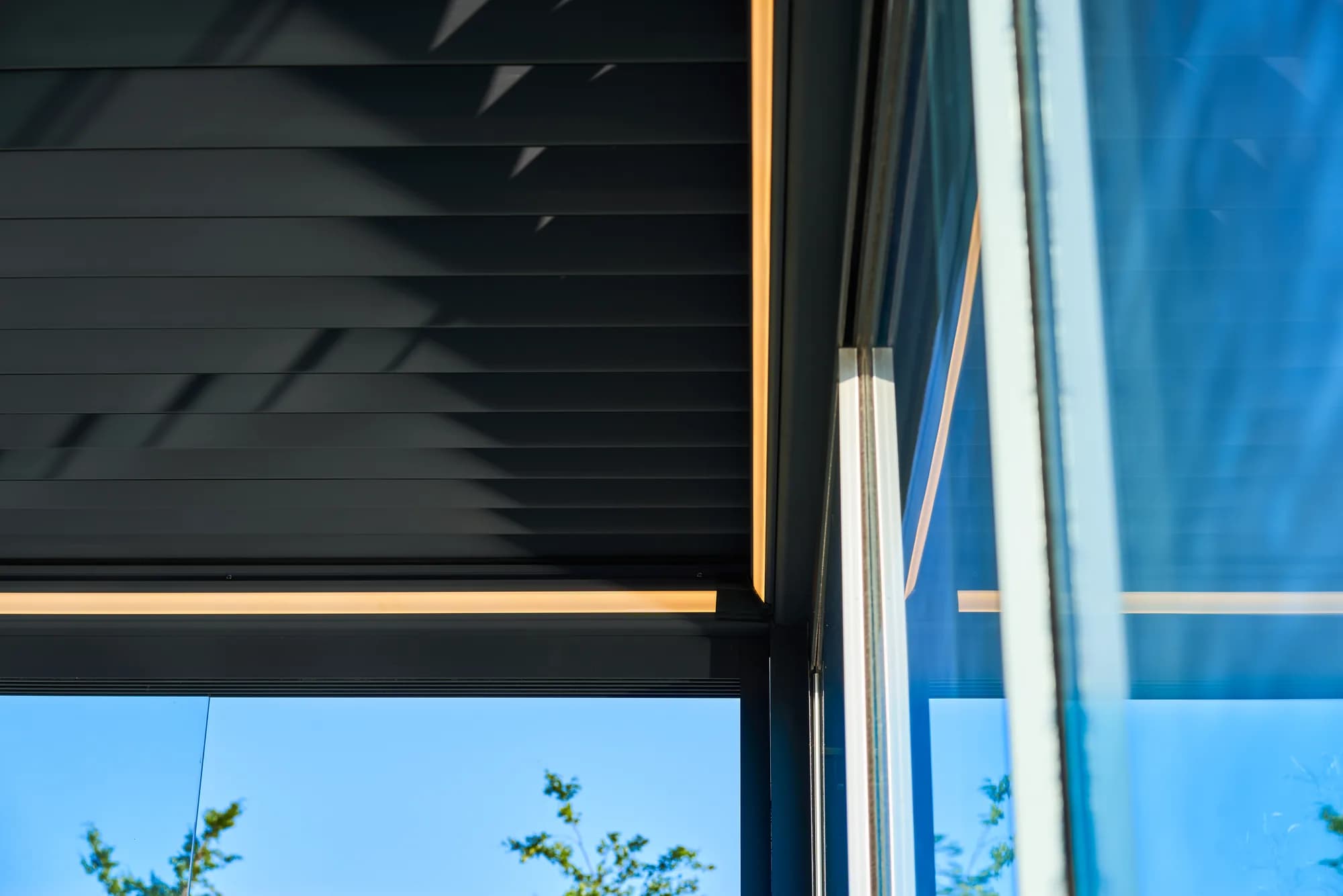 Pergola mit Lamellendach Pinela Deluxe aus Aluminium, Lamellen halb geöffnet über einer Terrasse